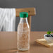 IKEA SPARTANSK clear glass water bottle green standing on a wooden table
