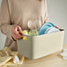 Person carrying IKEA SPJUTLILJA dish drainer by handle with plates and utensils inside