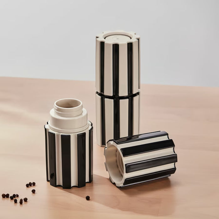 Hand grinding salt with IKEA SPJUTLILJA black and white striped spice mill over fresh salad