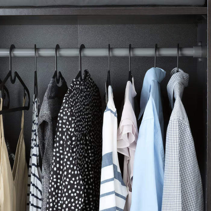 Multiple IKEA SPRUTTIG black hangers on wardrobe rail with clothes organised neatly