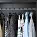 Multiple IKEA SPRUTTIG black hangers on wardrobe rail with clothes organised neatly
