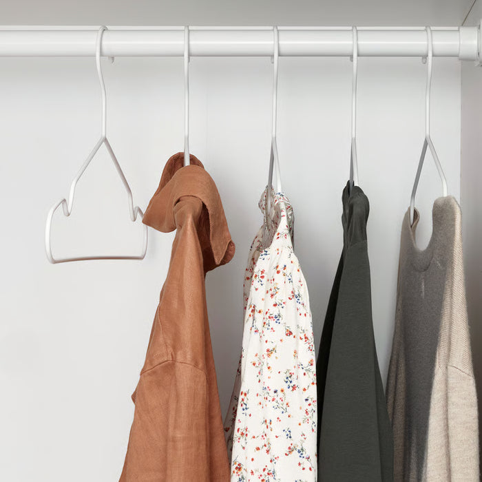 Four colourful garments hanging on IKEA STAJLIG slim white hangers neatly organised in wardrobe