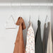 Four colourful garments hanging on IKEA STAJLIG slim white hangers neatly organised in wardrobe