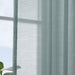 IKEA STENFRÖ turquoise sheer curtains framing a window above a radiator, bed with polka dot spread in view