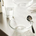 IKEA STRANDKRABBA clear glass bowl with hammered texture beside a spoon and water glass on a table