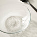 Close-up of IKEA STRANDKRABBA ribbed glass bowl casting shadows on a white surface with a spoon