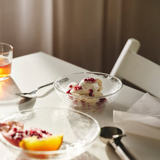 IKEA STRANDKRABBA glass bowl with rippled texture holding dessert topped with pomegranate seeds, spoon beside it