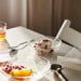 IKEA STRANDKRABBA glass bowl with rippled texture holding dessert topped with pomegranate seeds, spoon beside it