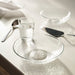IKEA STRANDKRABBA hammered glass deep plate with glass cup, knife and spoon on table