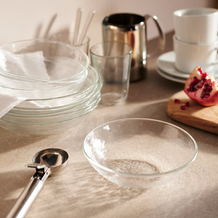 Stack of IKEA STRANDKRABBA clear glass deep plates, one holding sugar, hammered texture