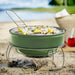 Green portable grill with food on a sandy beach