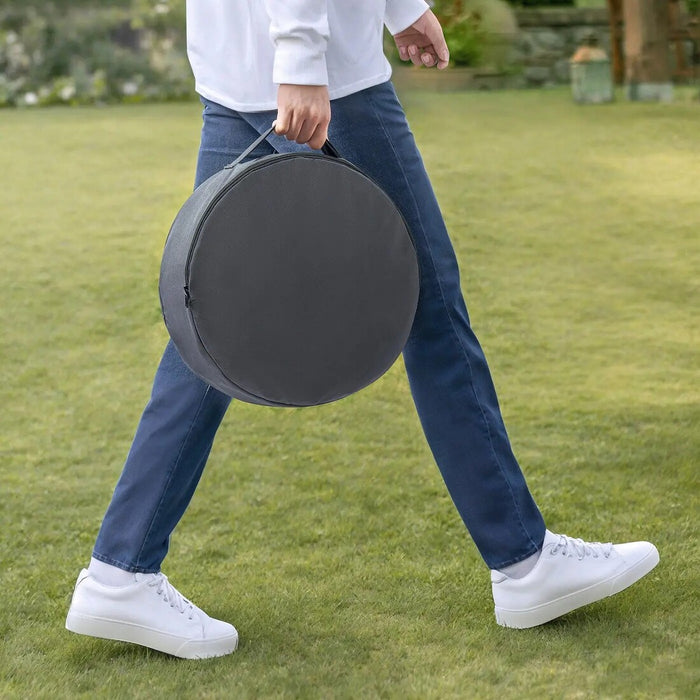 Person walking outdoors with a large round black object on a grassy area