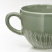 IKEA STRIMMIG stoneware mug pale grey-green close-up showing textured floral base and large handle 