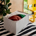 IKEA STUK storage box holding folded blankets on black and white striped fabric