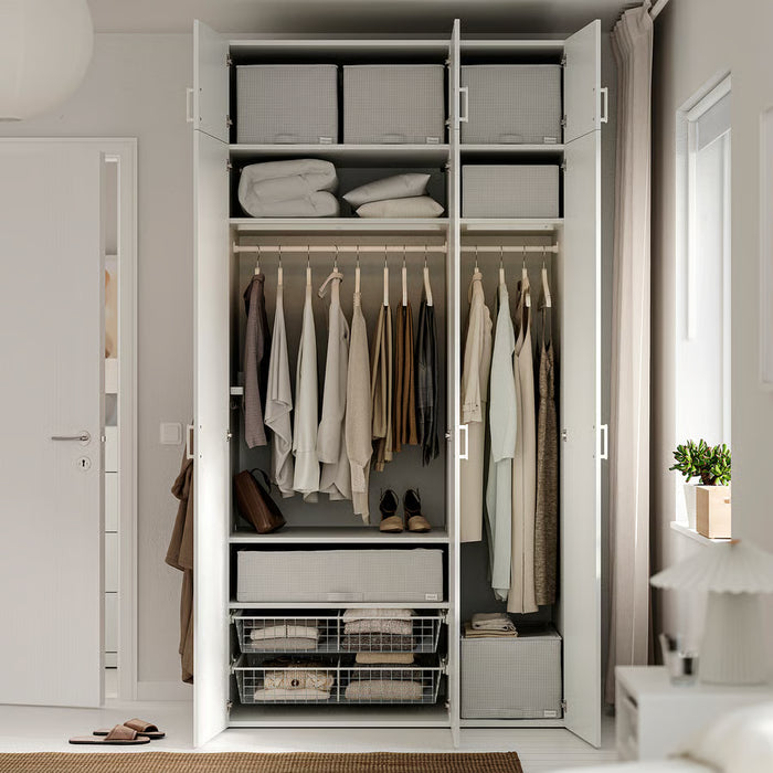 Open white wardrobe with hangers, folded clothes and IKEA STUK storage boxes inside