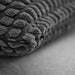 Close-up of IKEA SVARTPOPPEL anthracite cushion cover showing tactile raised pattern and pile texture