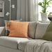IKEA SVARTPOPPEL light orange cushion cover styled on grey sofa in modern living room with green and geometric cushions