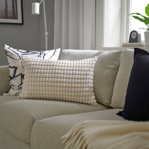 IKEA SVARTPOPPEL off-white cushion cover styled on a sofa with tufted texture visible