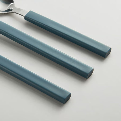 Three matte blue-gray chopsticks with a metal spoon, arranged diagonally on a light gray background.