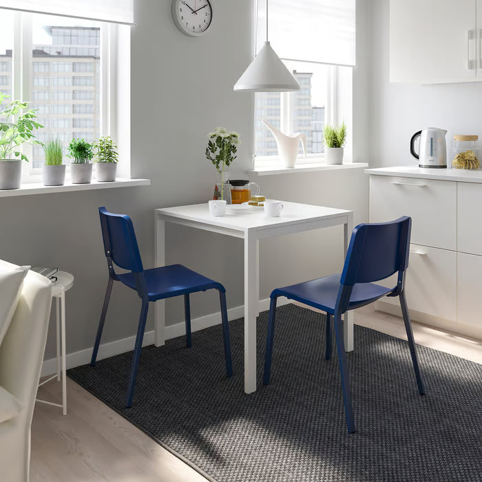 Two IKEA TEODORES blue chairs at small white kitchen table with plants minimalist decor