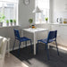 Two IKEA TEODORES blue chairs at small white kitchen table with plants minimalist decor