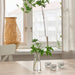 IKEA TIDVATTEN clear glass vase with single flower stem on wooden table near window