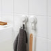 IKEA TISKEN white suction cup hooks holding grey hand towel and wooden spatula on kitchen tiles