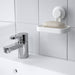  IKEA TISKEN white soap dish mounted on bathroom wall beside chrome tap with toothbrushes and plant