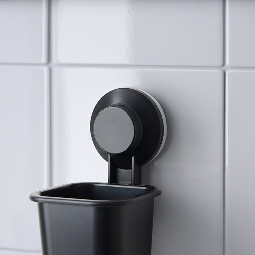 IKEA TISKEN black toothbrush holder mounted on tiled bathroom wall with suction cup
