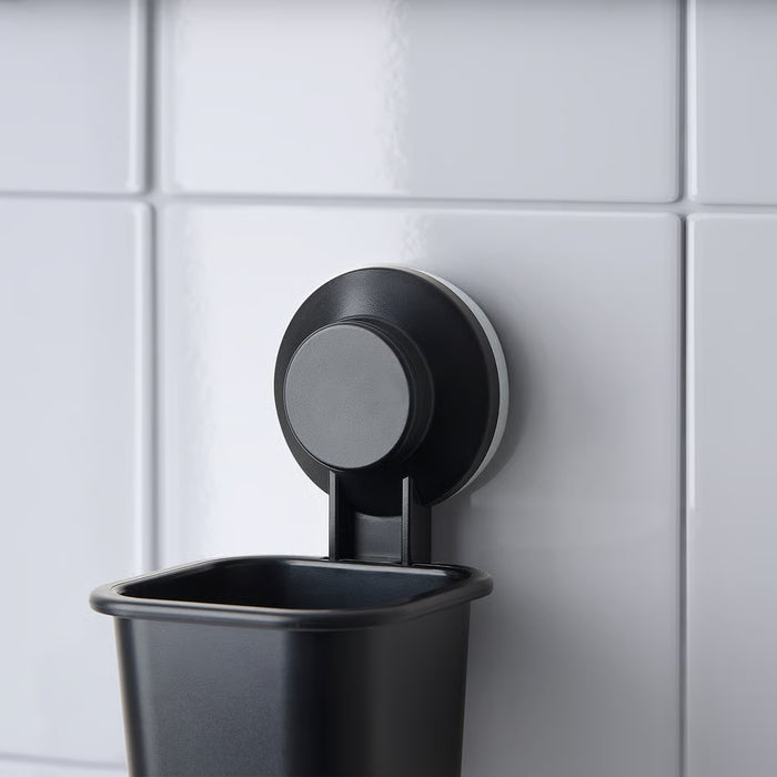 IKEA TISKEN black toothbrush holder mounted on tiled bathroom wall with suction cup