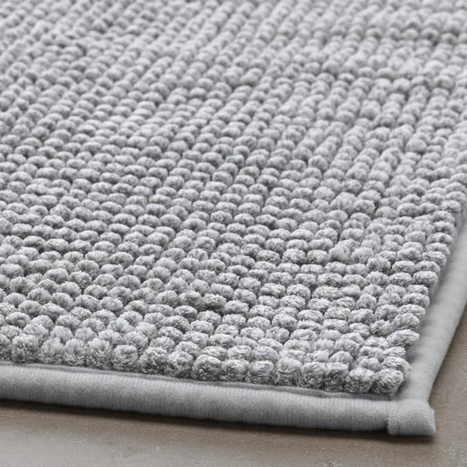 Close-up of IKEA TOFTBO grey-white bath mat folded showing soft microfibre surface texture