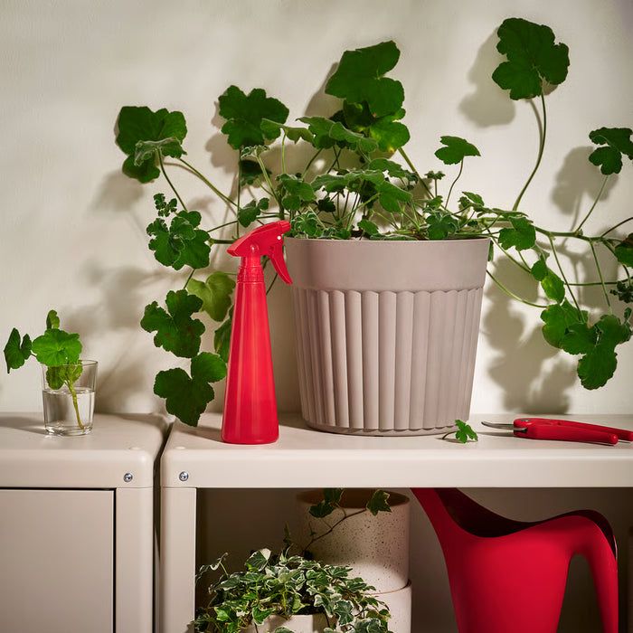  IKEA TOMAT red spray bottle styled with indoor potted plants on a shelf
