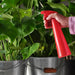 IKEA TOMAT red spray bottle held in hand showing grip and nozzle detail