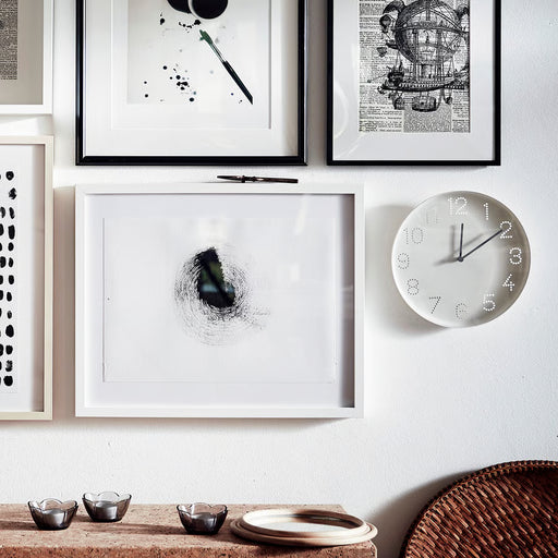 IKEA TROMMA white wall clock with black hands displayed above books and décor in a styled desk setup