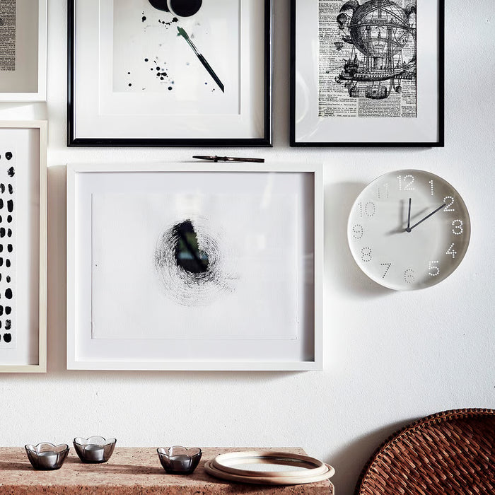 IKEA TROMMA white wall clock with black hands displayed above books and décor in a styled desk setup