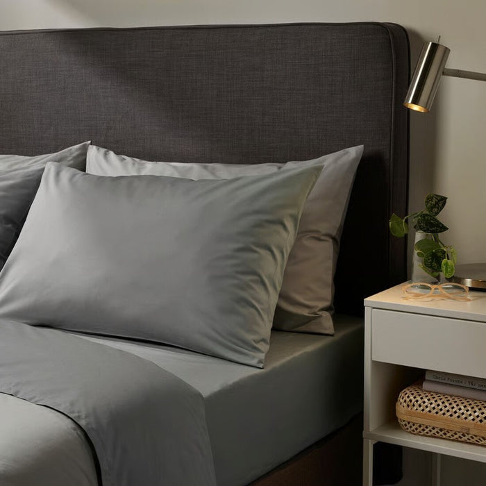 Gray bedding on a bed with a nightstand in a bedroom setting