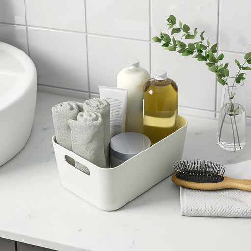 IKEA UPPDATERA white box used as bathroom organiser holding towels bottles and brush with handles