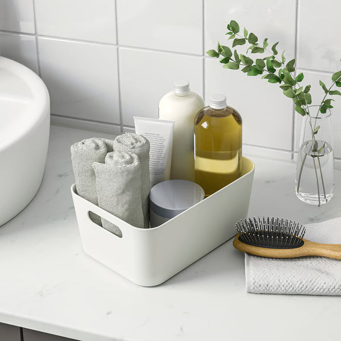 IKEA UPPDATERA white box used as bathroom organiser holding towels bottles and brush with handles