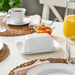 IKEA UPPLAGA small white butter dish placed between cups and jam on breakfast table