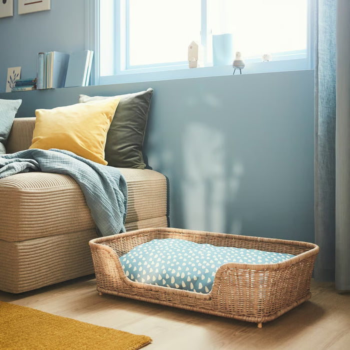 IKEA UTSÅDD blue pet cushion inside wicker pet bed placed beside an armchair, indoor home setting