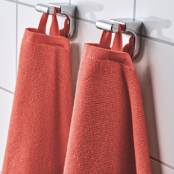 Two IKEA VÅGSJÖN orange bath towels hanging neatly on wall-mounted holders