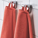 Two IKEA VÅGSJÖN orange bath towels hanging neatly on wall-mounted holders