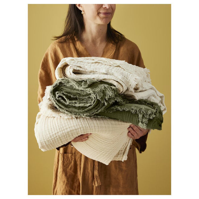 A person holding the IKEA VALLKRASSING Throw, off-white color, 150x200 cm (59x79 inches), perfect for warmth and comfort. 40570927