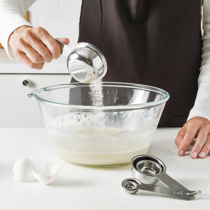 Person measuring sugar using IKEA VARDAGEN measuring spoon into a mixing bowl while baking