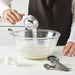 Person measuring sugar using IKEA VARDAGEN measuring spoon into a mixing bowl while baking
