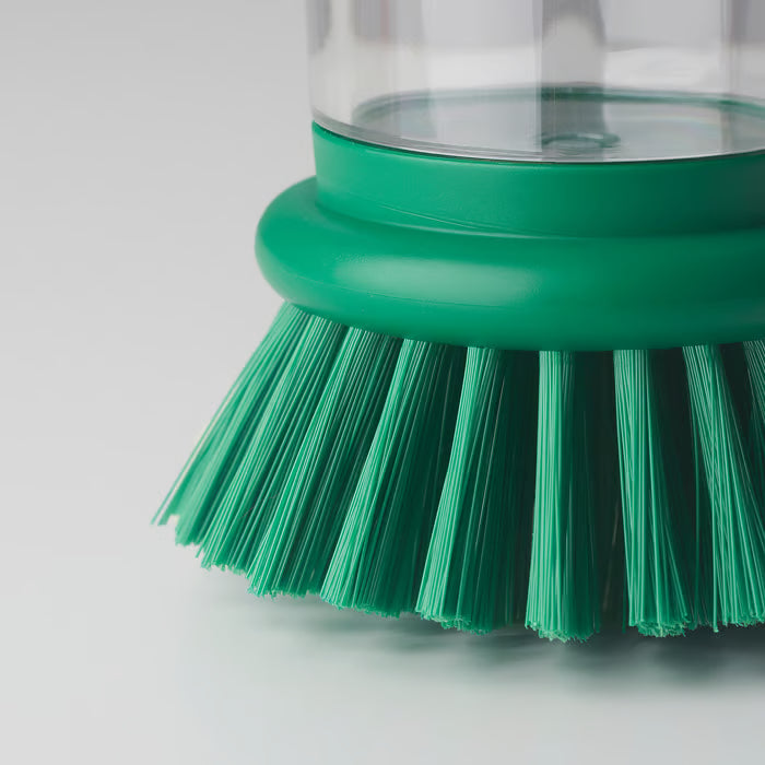 Close-up of IKEA VIDEVECKMAL green dish brush showing transparent handle, pressure dispenser system, and dense bristles