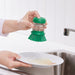 Person pressing IKEA VIDEVECKMAL green brush top to dispense soap onto a dirty plate in sink
