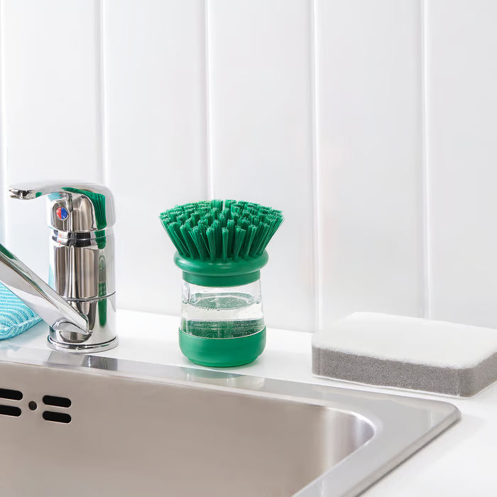 Kitchen sink styled with IKEA VIDEVECKMAL green dish brush, soap dispenser, and sponge alongside
