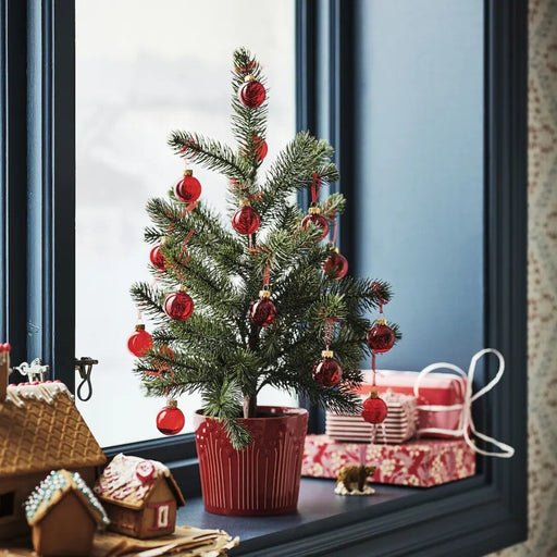 Close-up of a glossy red glass Christmas ornament with an attached hanging string.