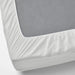 White fitted IKEA VIPPVEDEL mattress protector covering a gray mattress. Features elastic edges for a snug fit, quilted design for added comfort, and durable fabric for protection against dust and stains.